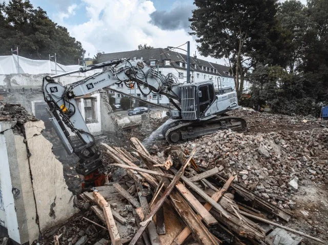 Bagger und rückgebaute hölzerne Dachbauteile