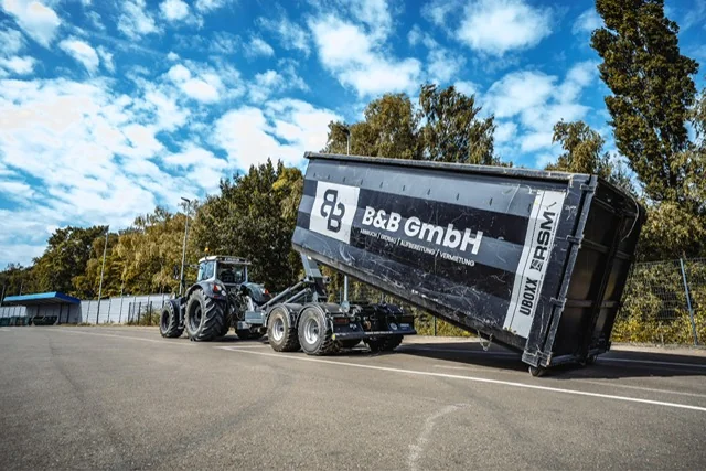Kippauflieger mit B&B-Beschriftung beim Materialtransport